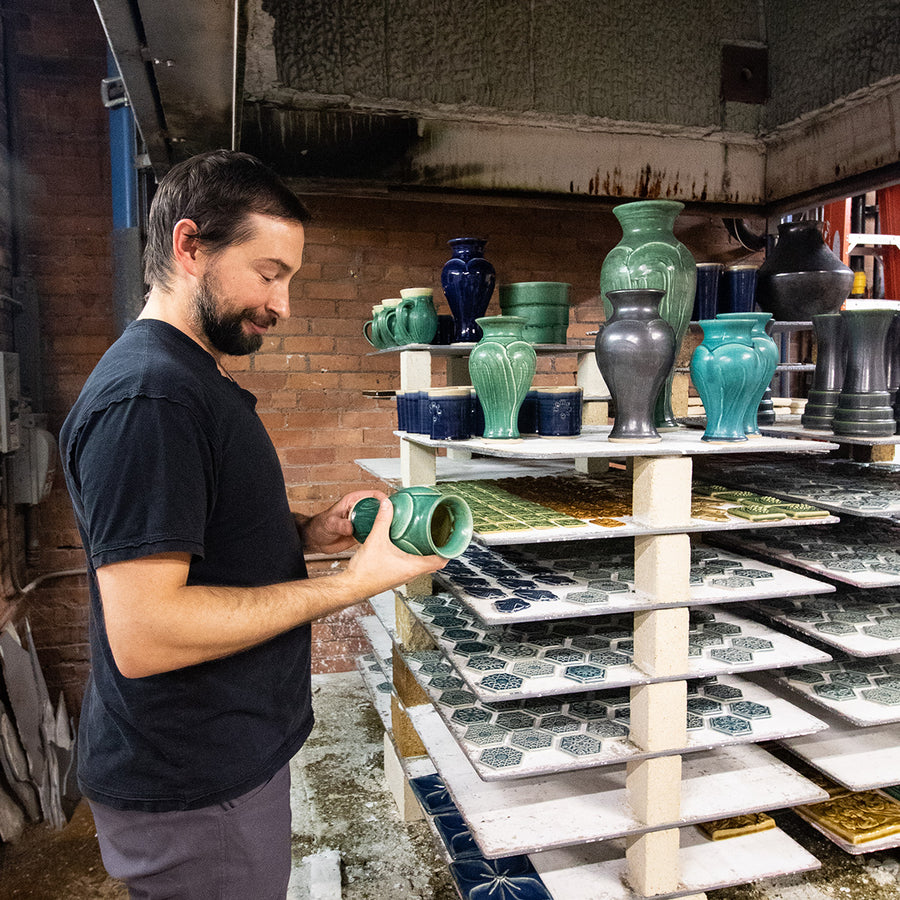 Kiln technician Brett inspects a Small Classic Vase in Pewabic Green glaze that just came out of Pewabic's large Blaauw Kiln