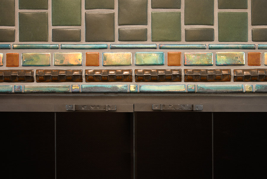 Details of the custom Iridescent glazed trim surrounding the opening of the fireplace. The metallic surface of these tiles stands out against the subdued bayleaf glaze. 