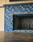 A blue iridescent tiled fireplace with accent tile around the center and custom-cut tile radiating from the center of the design. 