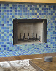 A close up shot of a blue iridescent tiled fireplace. The details in the accent tiles are more visible surrounding the fireplace's opening. 