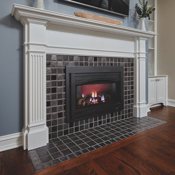 An angled view of a fireplace and hearth made up of charcoal and glossy black or "onyx" tiles. 