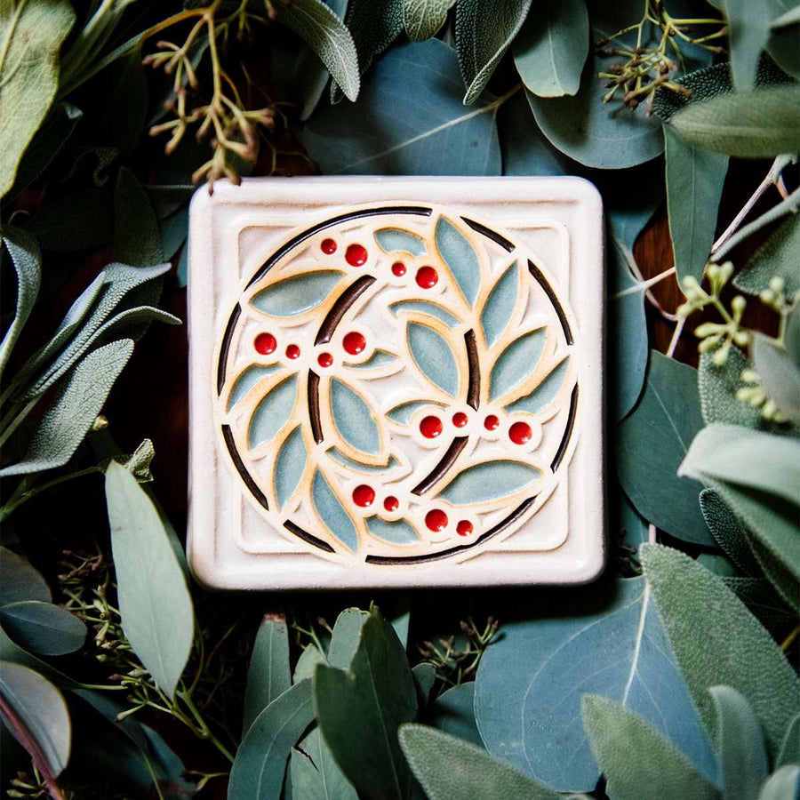 The DIA Leaf and Berries tile features two intertwined branches with round berries that create a circle at the center of the tile. The thick lined border makes the tile into a square. This tile features Style D with red berries, pale green leaves, brown stems and a white background.