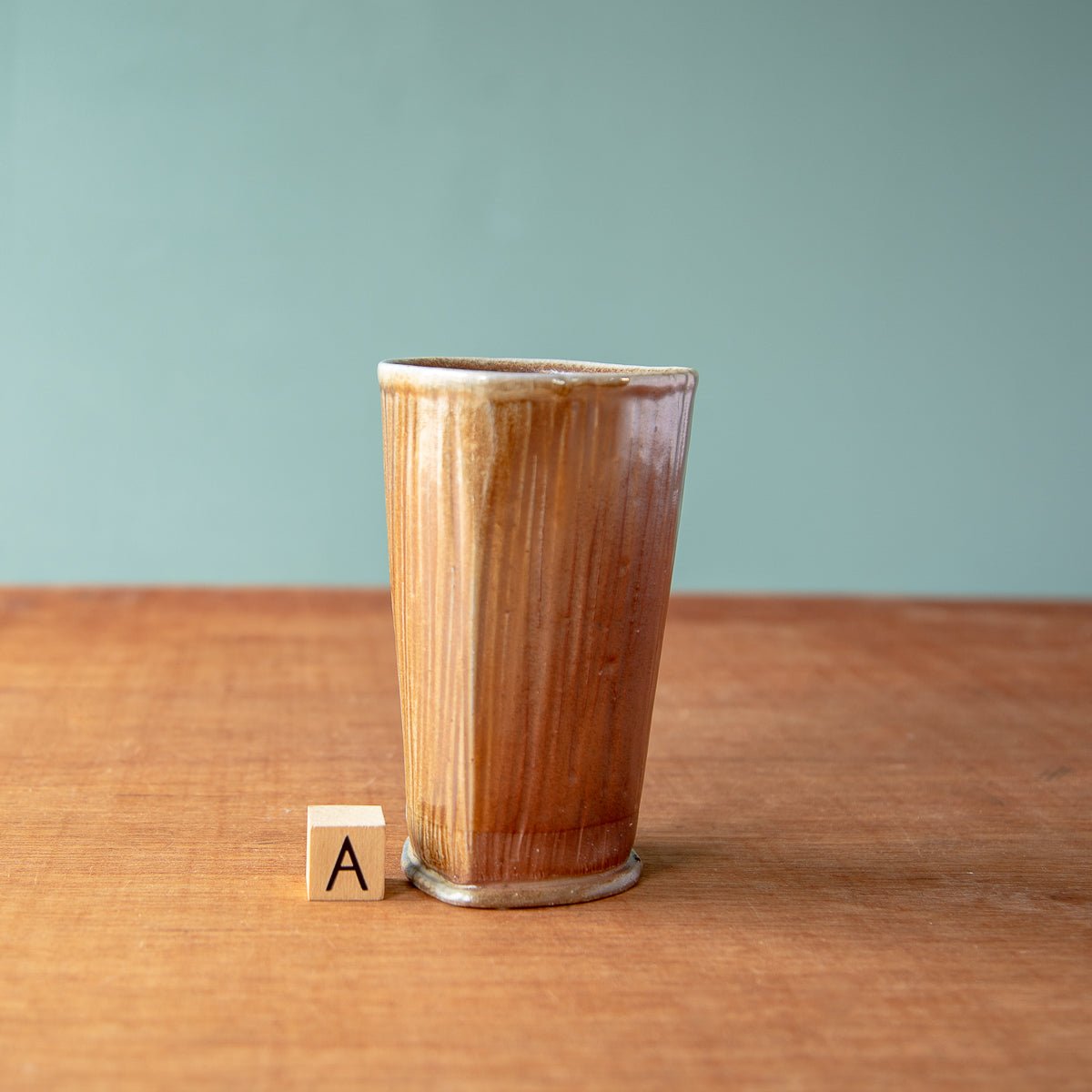 The style A pale brown tumbler boasts a semi-gloss glaze and a slight triangle shape.