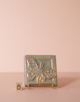 A butterfly tile sits on a stand next to the letter B to delineate which option is represented.