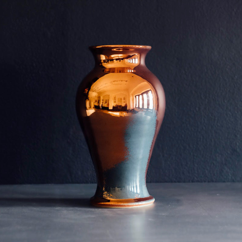 The Large Classic Vase starts with a small diameter at its base that gradually gets larger until it contracts again near the top with a slightly wider lip. The surface of the vase is smooth.