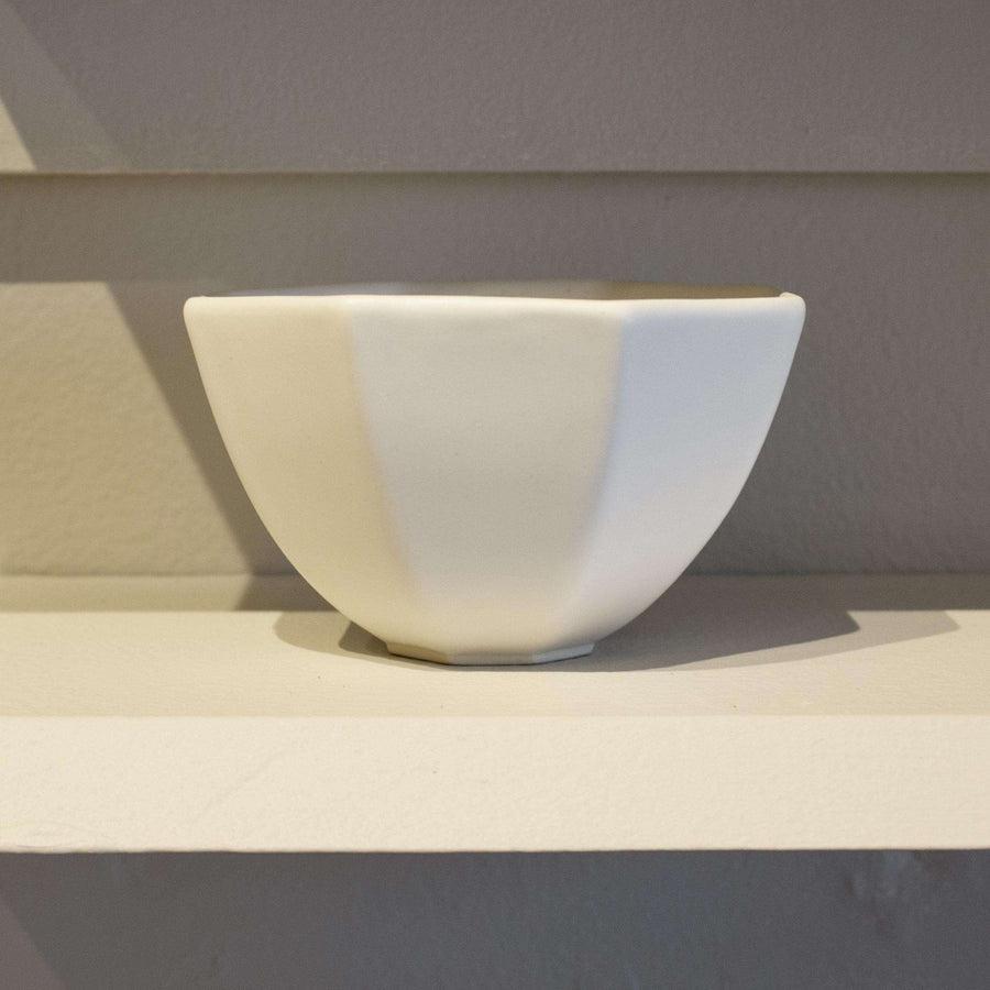 This is a small white cup with modern lines creating an eight sided-opening.