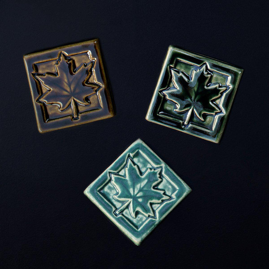 The tile features a large maple leaf with delicate veins reaching out the the tips of its ends. This tile has a simple square border.