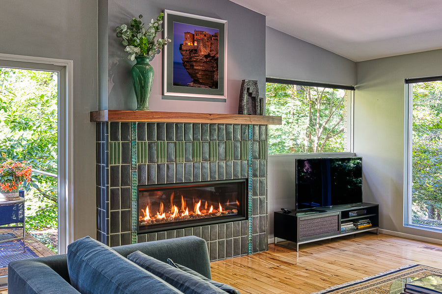 Angled view of a custom Pewabic fireplace incorporating Midcentury Modern design elements with an Aurora Iridescent Saarinen-inspired tile border.