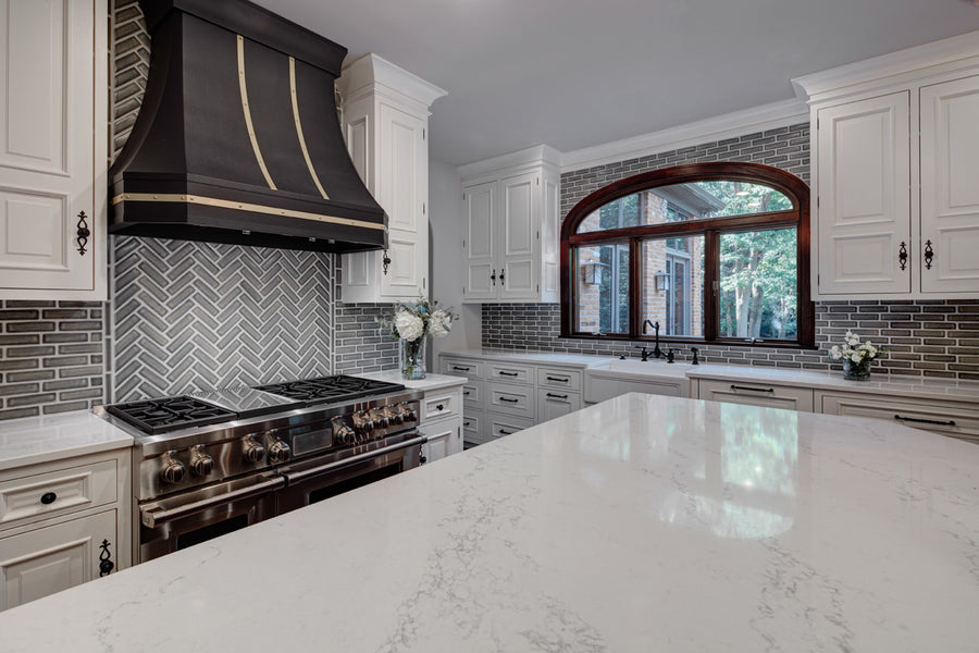 The entire kitchens boasts the bright whites of the counters and cabinets with the sleek gray tiles bahind.