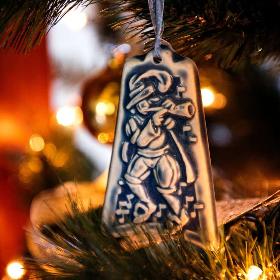 The Ceramic Eleven Pipers Piping Ornament is hanging on a Christmas tree.