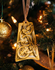 The ceramic Five Gold Rings Ornament hangs on a lighted Christmas tree with gold sparkling decorations.