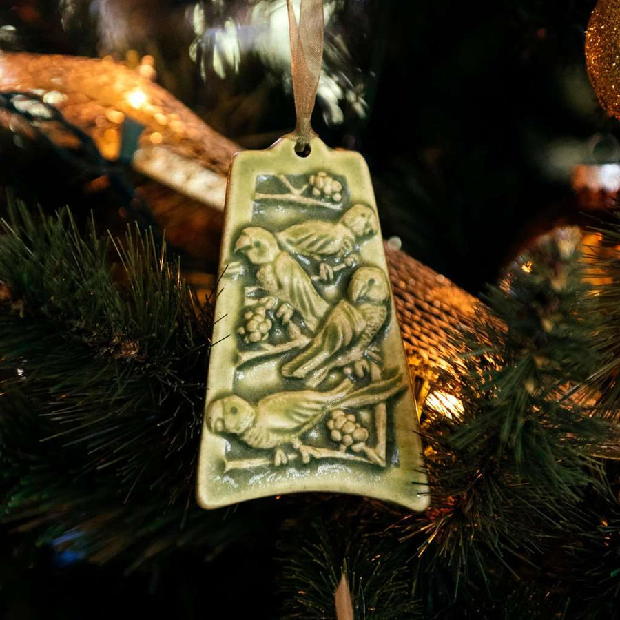 The ceramic Four Calling Birds Ornament hangs from a lighted Christmas Tree.