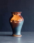 The Medium Classic Vase starts with a small diameter at its base that gradually gets larger until it contracts again near the top with a slightly wider lip. The sides of the vase are completely smooth.