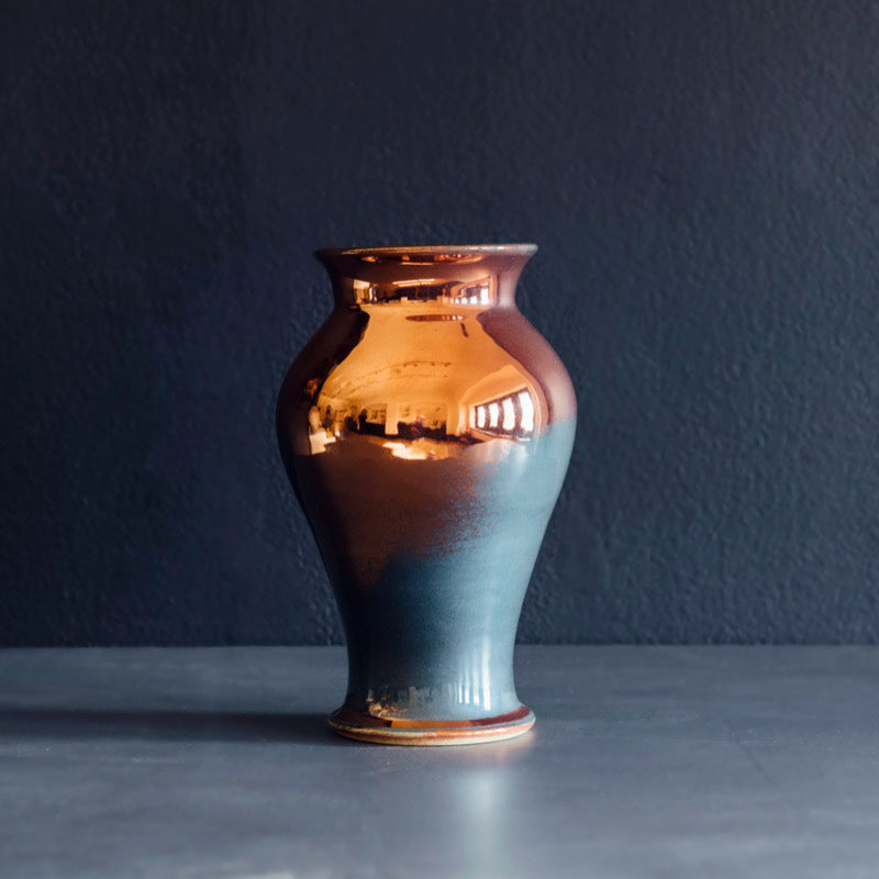 The Medium Classic Vase starts with a small diameter at its base that gradually gets larger until it contracts again near the top with a slightly wider lip. The sides of the vase are completely smooth.