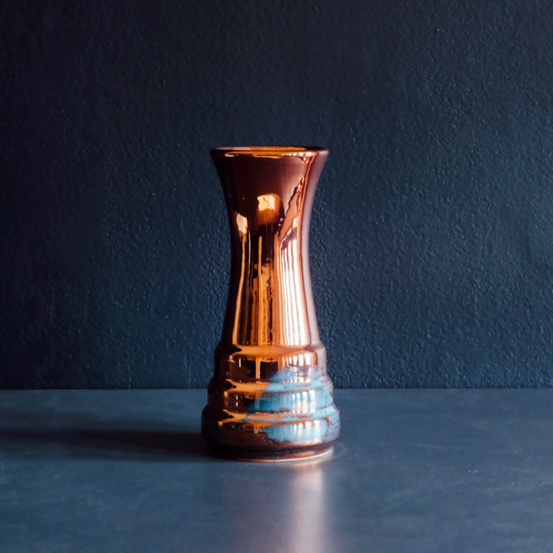 This vase is a sleek, slim vessel. At the base, there are three shallow "steps" with the widest at the bottom. The vase continues up in a smooth column that gets slightly wider at the top.