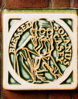 The Solanus Casey Tile features a line drawing of Solanus Casey from mid-chest up wearing glasses and a cloak while holding a Bible to his chest. The words "Blessed Solanus Casey" are curved around him, creating a halo-like circle. This tile is glazed in a glossy green color with the raised design being scraped giving it a creamy white hue.