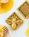 The Honeybee Tile features a large honeybee with stripes and detailed segmented wings. The bee sits on a honeycomb patterned background. These tiles features the matte golden yellow Mustard glaze.