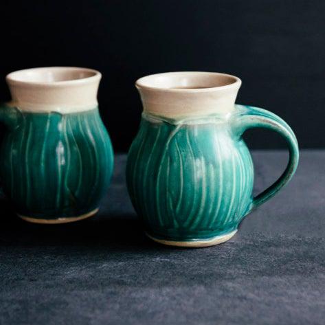 This mug features the matte turquoise Pewabic Blue glaze. The lip of the mug is cream colored.