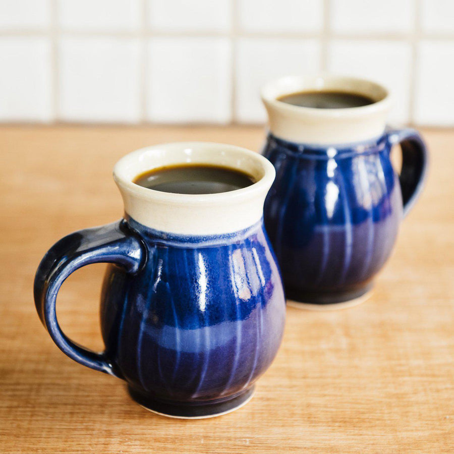 Two mugs sit together on a kitchen counter.