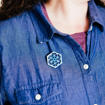 The small hexagonal Hex Pin features a line design of many interconnected triangles. The center has a tiny hexagon with a six-sided starburst emanating into the triangles.