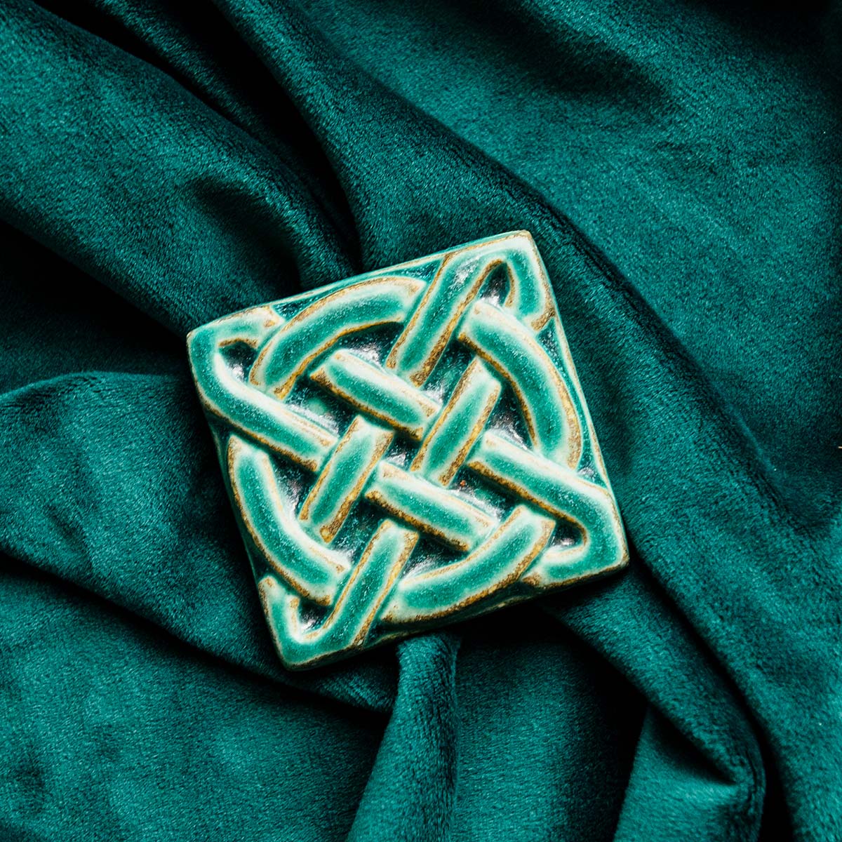 The Journey Knot Tile features two long ovals that create an x pattern with a large ring entwined with them.