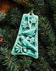 The bell-shaped Two Turtle Doves Ornament features two doves siting on the branches of a leafy tree.