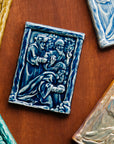 The Three Wise Men Tile features the wisemen in robes holding their three gifts- gold, frankincense and myrrh. They are all facing the right, they seem to be focused on one point. There is a stone wall behind them.