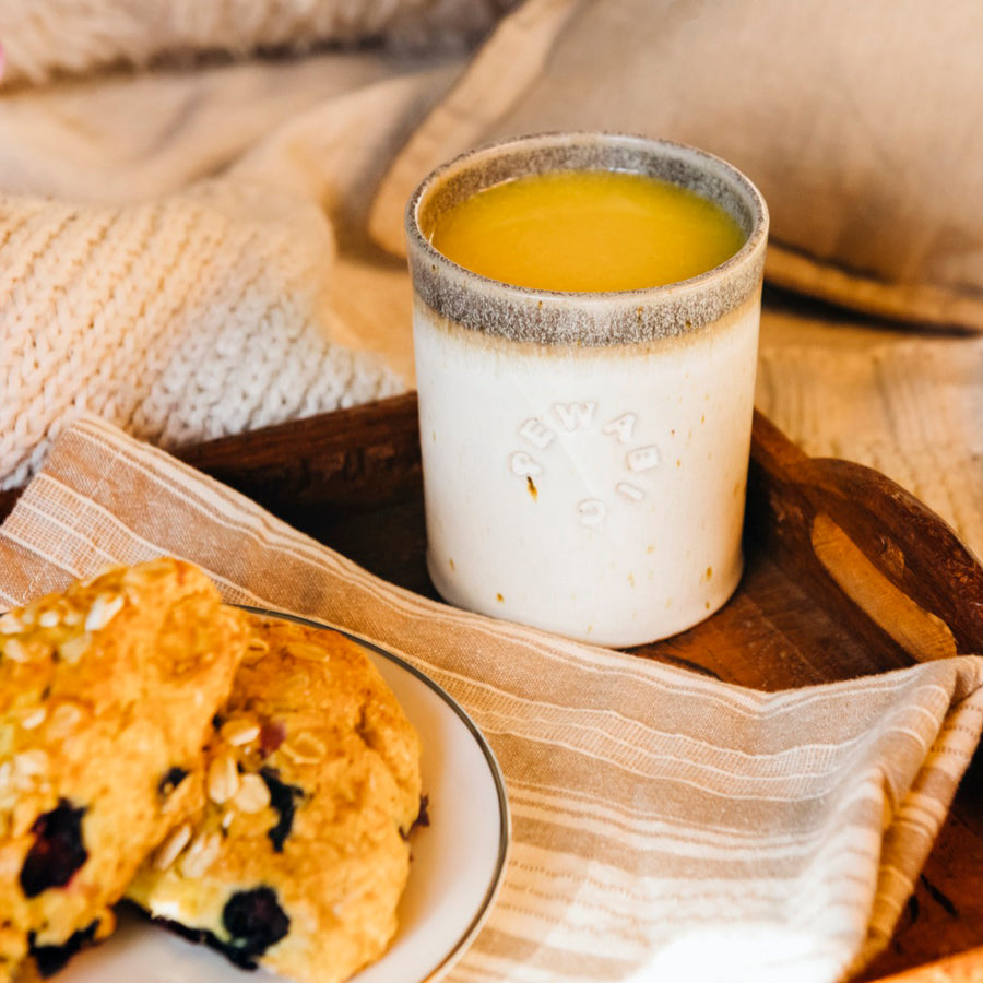 A Rocks cup filled with orange juice sits next to a plate covered in scones.