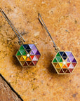 A pair of Hex Earrings rest on a brick surface.
