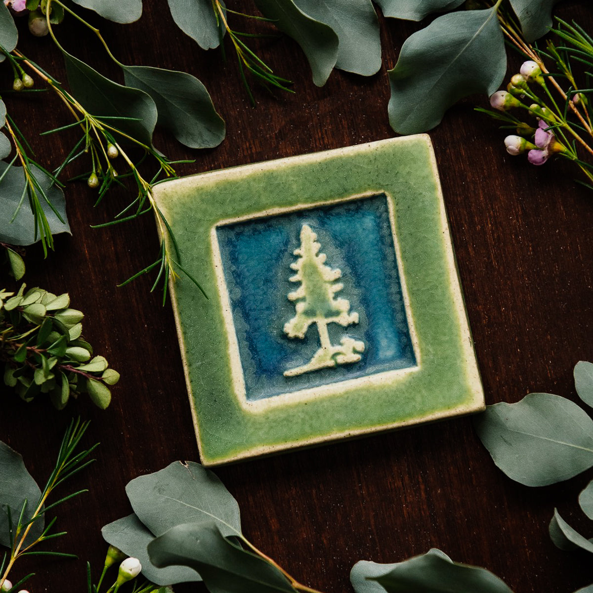 The Pine Tree Tile features a 3D outline of a pine tree inside of a thick, smooth square border.