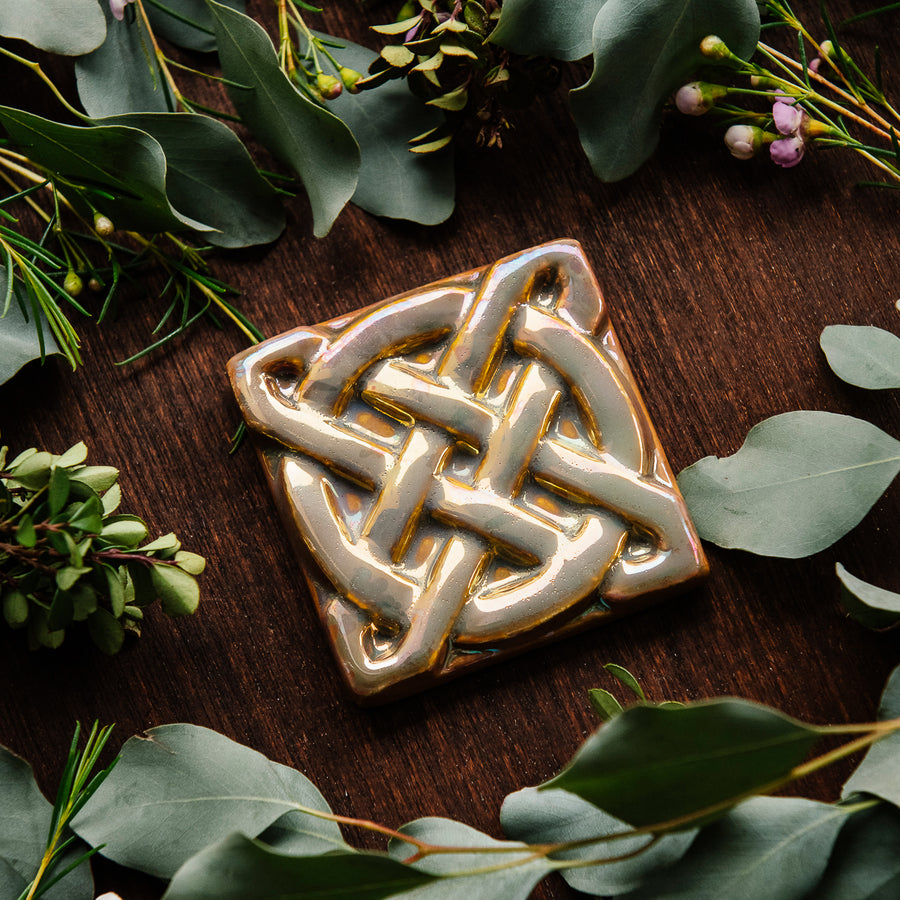 The Journey Knot Tile features two long ovals that create an x pattern with a large ring entwined with them.