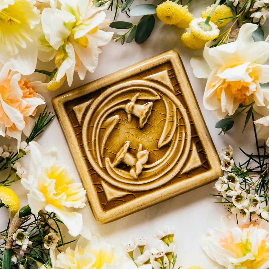 The Daffodil Tile features two flowers entwined in a circle with a strong square border around them.