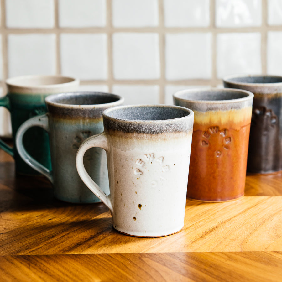 Five empty Cafe Mugs are set in a v pattern on a wooden countertop.