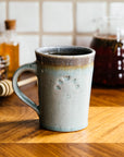 This Cafe Mug has a glossy pale blue Frost glaze with a gray colored interior.