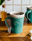 This Cafe Mug has a matte turquoise Pewabic Blue glaze with a cream colored interior.