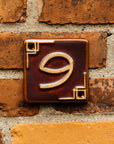 The Craftsman style ceramic 9 address number is in the satin reddish brown Carmine glaze option.