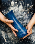 A Step Vase is held by a Pewabic artisan in a dusty denim apron.