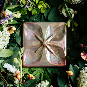 The Flower Geo Tile features a four-petaled flower. Each petal takes up a quarter of the tile, making a perfectly geometric shape. The inner part of the flower is round with four cattail shaped stamen exploding from the center that point out to the corners of the tile. 