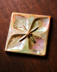 This Geo Flower Tile features the pinkish gold metallic Blush Iridescent finish which has many variations. Depending on the lighting in the room, these pieces will pick up different hues.
