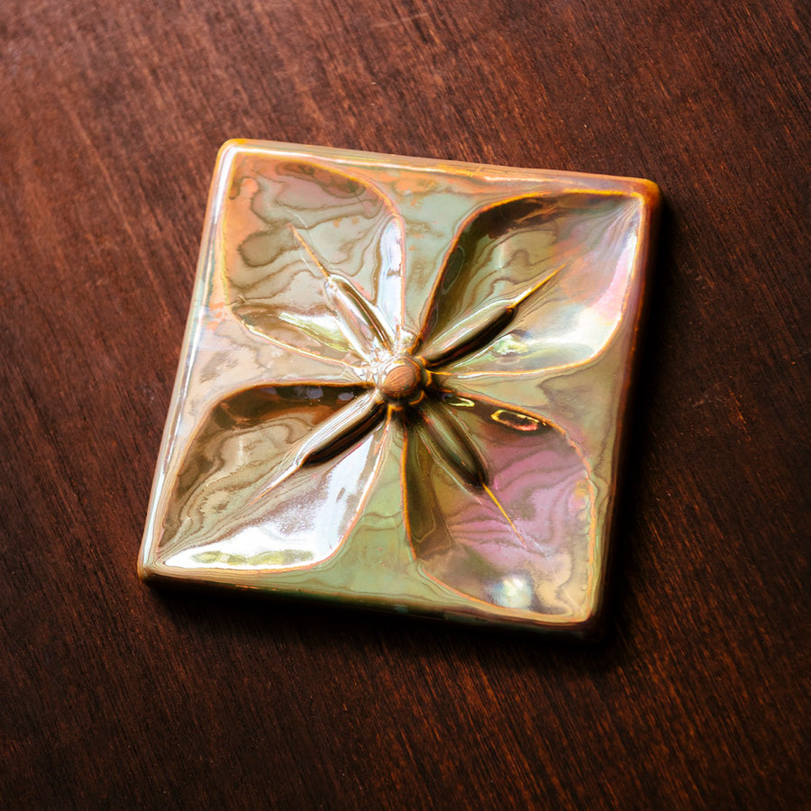 This Geo Flower Tile features the pinkish gold metallic Blush Iridescent finish which has many variations. Depending on the lighting in the room, these pieces will pick up different hues.