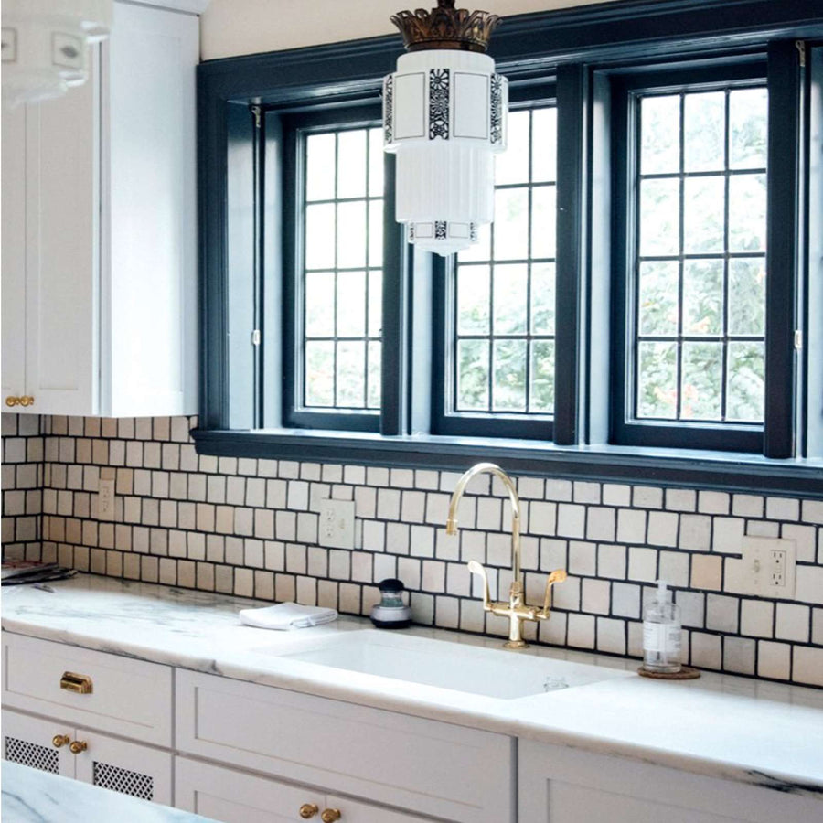 The rest of the Pewabic tile backsplash are pale shades of white with dark blueish grout.