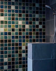 The moody blend of blues, greens, browns and whites are showcased on a large uninterrupted shower wall. The tiles are 3x3 square, all plain except for one which boasts the circular Pewabic logo.