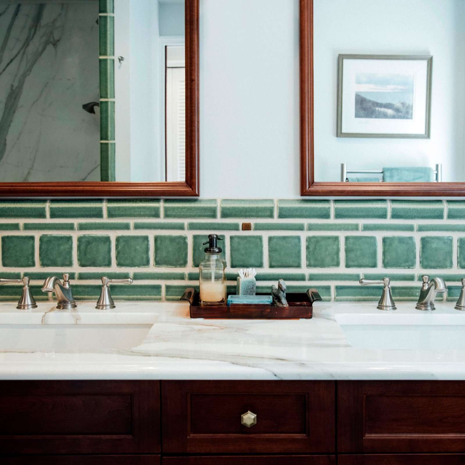 The green Pewabic tiles on the bathroom walls are like a thick border behind the double sink with white marble countertops.