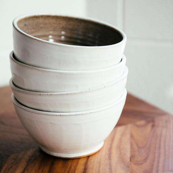 A stack of bowls feature the creamy white Birch glaze that has some natural brown speckling.