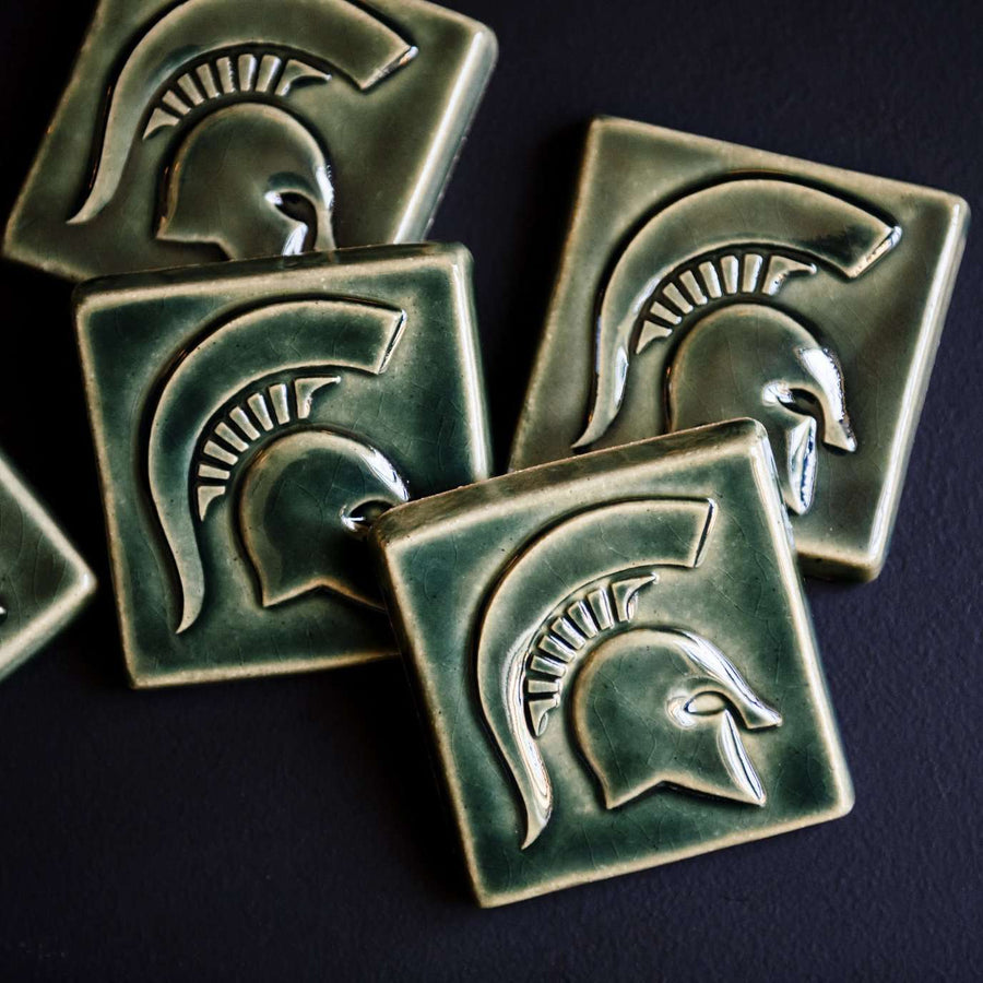 A pile of Kale colored tiles are scattered on a table.