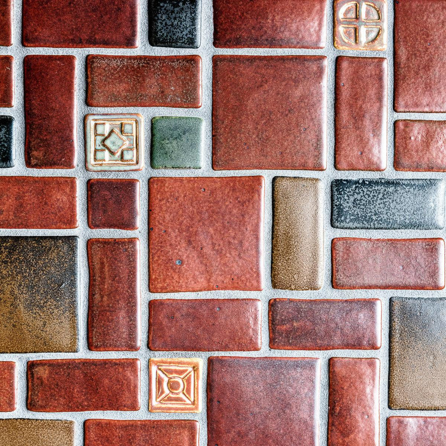 1:1 aspect ratio close-up shot of the red, tan, pine green, charcoal, and "blush" iridescent tiles in this autumnal design.