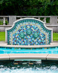 Outdoor poolside fountain in a range of glaze colors that look like the colorful plumes of a peacock. There are three hand-sculpted turtle sculptures at the center of the design in a blue-green glaze.