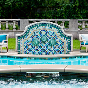 Outdoor poolside fountain in a range of glaze colors that look like the colorful plumes of a peacock. There are three hand-sculpted turtle sculptures at the center of the design in a blue-green glaze.