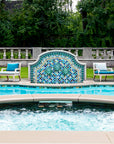 Outdoor poolside fountain in a range of glaze colors that look like the colorful plumes of a peacock. There are three hand-sculpted turtle sculptures at the center of the design in a blue-green glaze.