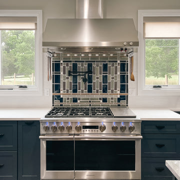 A custom kitchen backsplash prominently featuring glossy blue tiles that match the tone of the royal blue cabinetry.